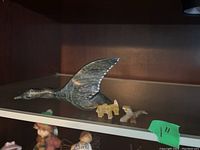 Large flying duck carving with small walrus and another small stone animal on shelf
