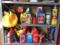Shelf with various automotive fluids and supplies such as Mothers cleaner wax, Fix-A-Flat tire inflator, Mobil oil, Fram oil filter boxes, and CLR cleaner.