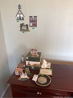 Overall view of wall hangings on wall and assorted house figurines, plate, and Irish handkerchief on wooden surface.