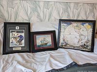 Three framed pictures displayed: a signed Bobby Hull and Johnny Bower hockey photo, a sailing ship print, and an old world map, all in black frames.