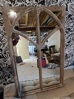 Photo showing the wood accented decorative mirror with arched top and paneled design in a room setting.