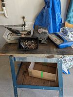 Dremel Maxpro rotary tool placed on a workbench with two plastic containers holding sanding wheels, drill bits, and buffing accessories.