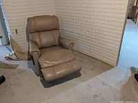 Front view showing light tan leather recliner with headrest, seat, and extended footrest