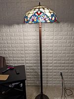 Full view of faux Tiffany floor lamp showing colorful stained glass globe, tall stand, base and power cord
