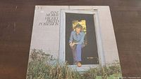 Front cover of the Anne Murray Highly Prized Possession vinyl record album showing Anne Murray seated in doorway wearing casual blue attire.