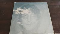 Front cover of the John Lennon Imagine vinyl album showing a faded monochrome portrait of Lennon with clouds.