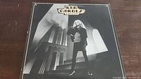 Front cover of Kim Carnes Voyeur vinyl album showing photograph of Kim Carnes on stairs against modern architecture