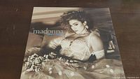 Front cover of Madonna Like A Virgin album showing Madonna in lace outfit on bed with flowers.