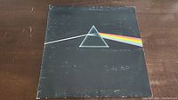 Front cover of Pink Floyd The Dark Side Of The Moon vinyl album showing iconic prism and light beam artwork with some wear and scuffs.