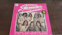 Front cover of The Best of Stampeders album in pink with band photo and title text.