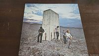 Front cover of The Who's 'Who's Next' vinyl record album showing band members beside a large concrete structure in a rocky outdoor setting under a partly cloudy sky.