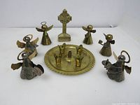 Image shows all small brass and silver plated Christmas items arranged with the round candle holder in the center surrounded by three brass angels and three silver plated brass angels, along with a brass Celtic cross standing at the back.