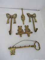 Photo displaying all five brass key holder hooks as a set arranged on a white backdrop.