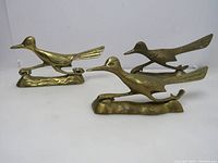 Three brass road runner figurines displayed showing full front and side angles, highlighting length, shape, and details.