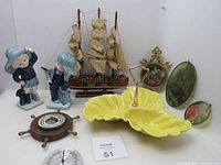Photo showing entire collection with yellow ceramic dish, porcelain figurines, handcrafted ship, barometer in ship wheel, and sun catchers