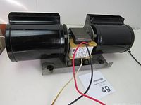 Photo showing the black metal dual-fan wood stove fan with wiring and metal base.