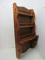 Front angled view of the wooden spice rack showing three shelves, curved sides, and brown coloration.
