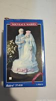 Photo of boxed Sabre wedding cake topper with bride and groom in vintage style on blue box labeled Nouveaux Maries