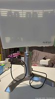 Front view of Carex Day Light therapy lamp showing the translucent white light panel with 'day light' branding and metallic silver stand and base. Black power cable visible.