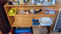 Photo of a wooden bookshelf with various items placed on it, which are not included with the lot. Bookshelf is empty for sale.