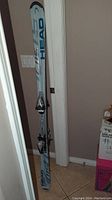 Photo of two Head alpine skis standing upright against a wall, showing bindings mounted and surface condition.