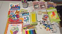 Wide shot of all kids craft items including plaster figures, paint pots, markers, clay, origami paper kits and foam kits