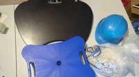 Top view of blue wheelie toy base, black lap desk, blue hard hat and packaged hammock