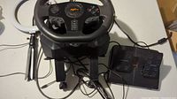 PXN V900 racing wheel with base and pedals on a table, adjacent ring light stand visible