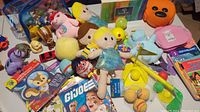 Multiple small children's plush toys, plastic toys, and books displayed together