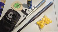 Photo showing two adult baseball bats (one Easton), four wooden pickleball paddles, white pickleballs, and a black Gonex bag with yellow plastic balls.