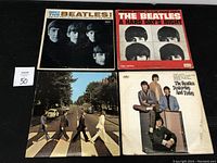 Four vinyl record albums by The Beatles displayed on a flat surface, visible wear on covers.
