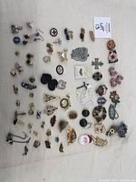 Overview of all pins, earrings, and brooches laid out on white fabric background.