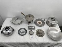 Overview of entire collection of vintage cooking ware items on white cloth