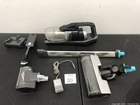 Full set of Bissell cordless vacuum cleaner with all attachments laid out on black surface