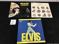 Three vinyl records: 'Elvis Aloha from Hawaii via Satellite', 'Elvis The Wonderful World of Christmas', and a blue Elvis single