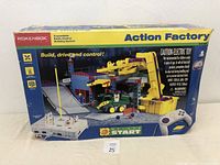 Front view of the Rokenbok Action Factory building construction toy set box showing the crane, vehicles, and the remote control included.