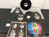Vinyl single record on top with Kiss band member poster beneath and Dynasty album cover to side