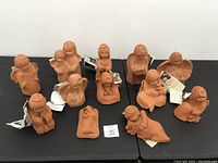Photo showing 12 clay sculptures arranged on a black table with identifying lot number 35