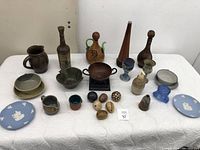 Full view of all pottery and decorative items on white cloth, showing variety of shapes and sizes.