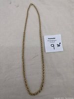 Full view of a gold plated rope style necklace laid flat showing its full 30 inch length and chain design.