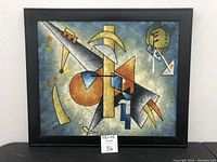 Full front view of the abstract painting in black frame showing geometric shapes and colors.