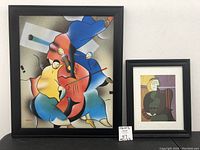 Photo showing the pair of framed artworks side by side on a white wall, with size tags below.