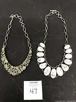 Two vintage custom sterling silver necklaces displayed side by side on a black fabric surface.