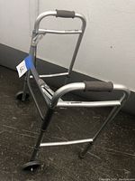 Side angle showing aluminum frame, foam padded handle, and front wheels on walker.