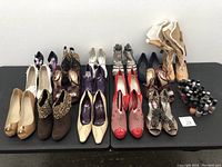 Photo showing 14 pairs of women's shoes in various styles and a collection of nail polish bottles on a black surface against a white wall.