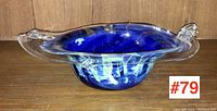 Front angle of the art glass bowl showing its wide clear rim, blue and white swirl interior, and handle detail.