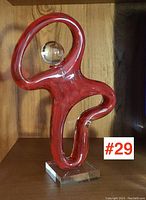Full front view of the red glass dancing man figurine with clear spherical head and clear glass base.