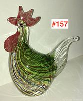 Front and left side view of colorful art glass rooster figurine featuring red comb and wattles and swirl patterns in body.