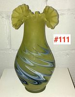 Front view of vase showing satin yellow-green finish with blue and white swirl patterns and ruffled top.