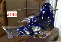 Side view of the blue art glass bird, showing detailed tail and wing feathers with clear and blue glass blending.